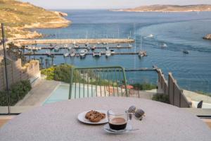 MġarrGozo Harbour Views, Mgarr Heights的一张桌子,上面放着一盘食物和一杯葡萄酒