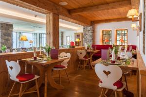 费斯恩AllgäuHotel Tanneck的配有木桌和白色椅子的餐厅