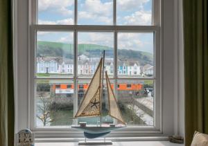 阿博伦Angorfa Aberaeron Apartment的一只玩具帆船坐在窗户上,享有美景