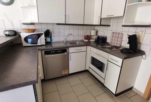 卡尔斯哈根Fewo Sommergarten 4005_OLIV的厨房配有白色橱柜、水槽和洗碗机。