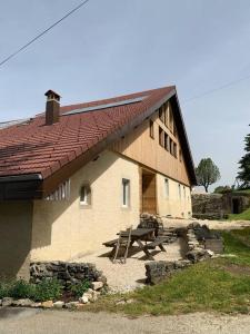 MontperreuxAncienne ferme comtoise 4 étoiles, 11 personnes Lac St-Point/Mont d'Or的前面有一张野餐桌的建筑