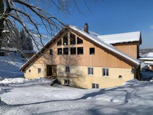 MontperreuxAncienne ferme comtoise 4 étoiles, 11 personnes Lac St-Point/Mont d'Or的前面的谷仓里积雪