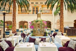 伦敦伦敦龙马酒店的一间设有桌椅的餐厅,种植了棕榈树