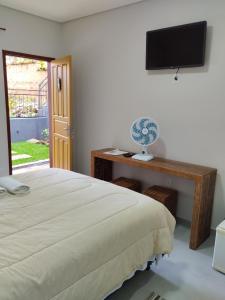蒂拉登特斯Pouso Casa da Vovó的一间卧室配有一张床和一张书桌上的电视