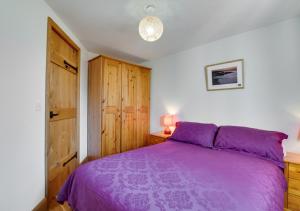 ElerchBrynmeurig的一间卧室配有紫色的床和木制橱柜
