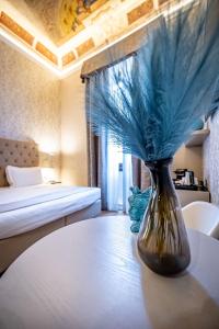 佛罗伦萨Martelli 6 Suite & Apartments的一张穿着蓝色羽毛坐在房间桌子上的花瓶
