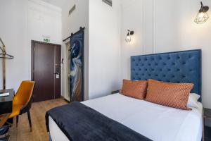里斯本Lisbon 5 Hotel的一间卧室配有一张带蓝色床头板的床和一张书桌