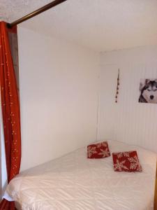 欧特吕斯Appartement chalet en plein centre des Saisies的一间卧室配有一张带两个红色枕头的床