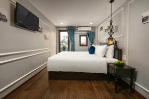 河内La Renta Hotel & Spa的卧室配有白色的床和电视。