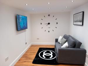 ErithHeronsgate GH013的客厅配有沙发和墙上的时钟