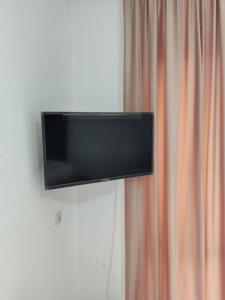 古达乌塔Diamond Eco Hotel的挂在窗帘旁墙上的平面电视