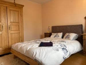罗塞姆Les Pommiers - Chambres dans maison privée的一间卧室配有一张大床和木制床头板