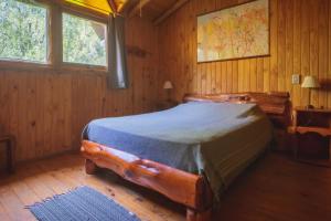 埃博森Cabañas Kairós的木制客房内的一间卧室,配有一张床