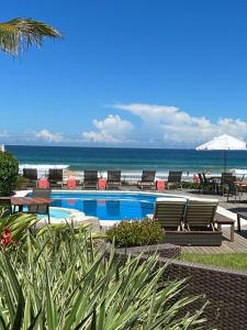 布希奥斯Maravista Hotel & Spa Ltda的一个带椅子的游泳池,背景是大海