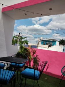 梅里达T´úubul K´iin Bed & Breakfast的一个带桌椅的庭院和粉红色的墙壁