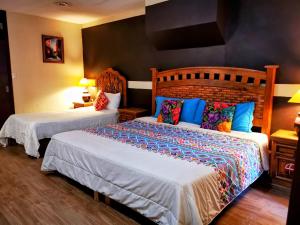 瓜纳华托Hotel Chocolate Tradicional的一间卧室配有两张带色彩缤纷枕头的床