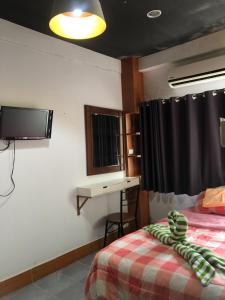 卡伦海滩KANWARA MASSAGE APARTMENT的一间卧室配有一张床、一张书桌和一台电视