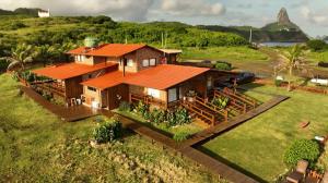 费尔南多 - 迪诺罗尼亚Pousada Naonda的绿色田野上一座带橙色屋顶的房子