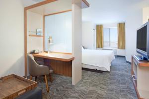 威奇托Springhill Suites by Marriott Wichita East At Plazzio的酒店客房设有一张床、一张书桌和一台电视机。