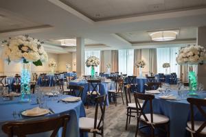 劳德代尔堡Fort Lauderdale Marriott North的宴会厅配有蓝色的桌椅和鲜花