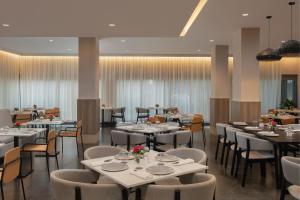 圣多明各圣多明各万怡酒店的用餐室配有白色桌椅和桌子。