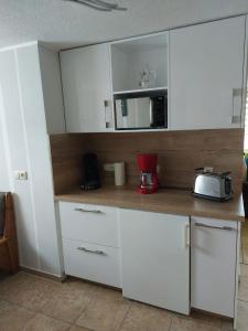 伊尔梅瑙Ferienwohnung Glasperlenfloh的厨房配有白色橱柜和微波炉