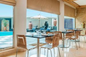 迪拜艾美航道酒店的一间带桌椅的用餐室和大窗户