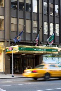纽约纽约曼哈顿/市中心东区庭院酒店的一辆黄色出租车驶过悬挂着旗帜的建筑