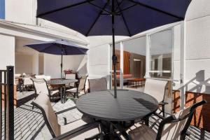 西沃威克华威普罗维登斯西春季山丘套房酒店的庭院内桌椅和遮阳伞