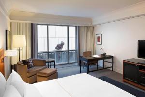 墨尔本墨尔本威斯汀酒店的配有一张床、一张书桌和一扇窗户的酒店客房