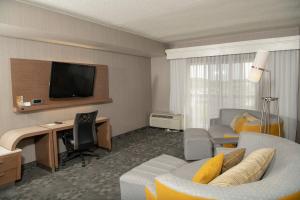 伊利伊利大使会议中心万怡酒店的酒店客房设有一张沙发和一张带电视的书桌。
