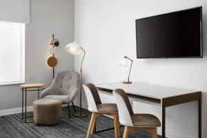 普兰特城TownePlace Suites by Marriott Plant City的客房设有书桌、两把椅子和电视。