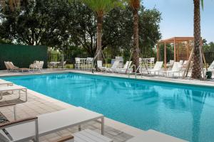 奥兰多Element Orlando Universal Blvd.的一个带白色躺椅的游泳池,棕榈树