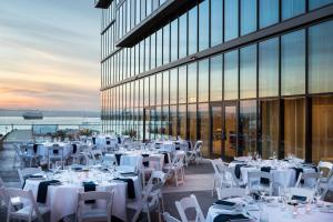 圣地亚哥万豪圣地亚哥市中心/海湾春季山丘套房酒店的一间设有白色桌椅的餐厅,以及一座建筑