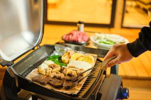 淡路Rush Awaji - Seaside Holiday Home - Self Check-In Only的一个人在烧烤架上烹饪食物