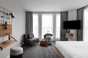 圣艾修伯里Moxy Lyon Airport的酒店客房配有一张床、一把椅子和一台电视。