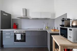 卡威尔奎Lyon Cite-La suite Passerelle avec balcon-Caluire的厨房配有水槽、炉灶和微波炉