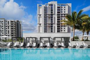迈阿密AC Hotel By Marriott Miami Brickell的一座带椅子的游泳池,一座高高的建筑