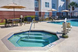 杰克逊维尔Residence Inn by Marriott Jacksonville Butler Boulevard的一个带桌子和遮阳伞的游泳池