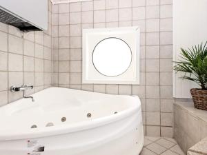 埃贝尔托夫特6 person holiday home in Ebeltoft的浴室设有白色浴缸,配有圆镜子