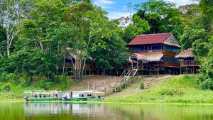 ParaísoYaku Amazon Lodge & Expeditions的河边的房屋,有船