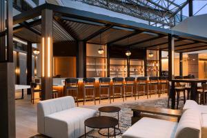 罗缪勒斯底特律大都会喜来登酒店机场店的一间酒吧,配有白色的沙发和酒吧凳子