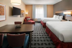 克洛维斯TownePlace Suites Fresno Clovis的酒店客房带两张床和一张桌子以及椅子。