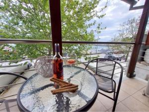 斯基亚索斯镇PORT SEA VIEW - SKIATHOS的阳台上的玻璃桌和一瓶葡萄酒