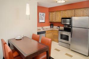 罗斯芒特芝加哥奥东公寓式酒店的厨房配有桌子和不锈钢冰箱。