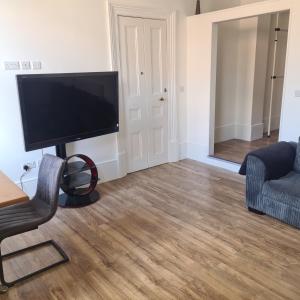 特伦特河畔伯顿Cozy apartment in Burton town centre的客厅配有平面电视和椅子。
