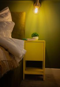 克卢日-纳波卡Smiling Apartment的一张黄色桌子,上面有植物,放在床边