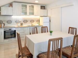 PetrovecMy Parents Guest House的一间带桌椅的厨房和一间带白色橱柜的厨房