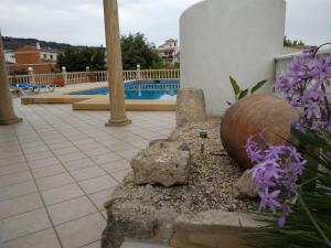 哈维亚Casa Maria Cecília的一张石椅,坐在一个种着紫色花的游泳池旁