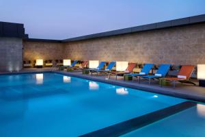 利雅德利雅得雅乐轩酒店的砖墙旁的游泳池,配有躺椅